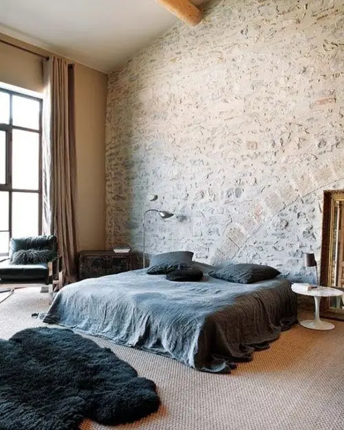 spacious bedroom with rough brick wall