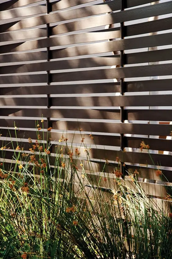 Woven Metal Slat Fence: Metal slats woven over and under the rails instead of screwed flat