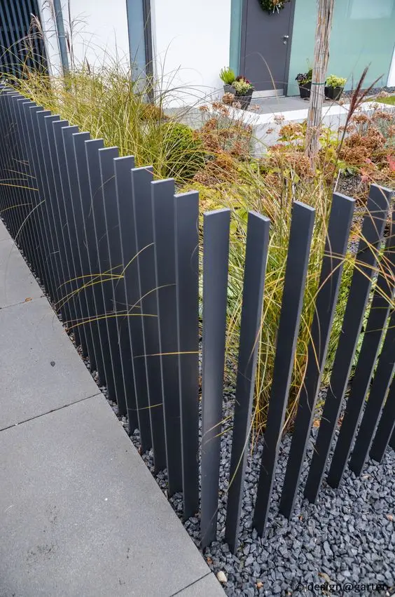 Free-Standing Iron Slats fence: A line of free-standing iron blades, each set separately into the ground