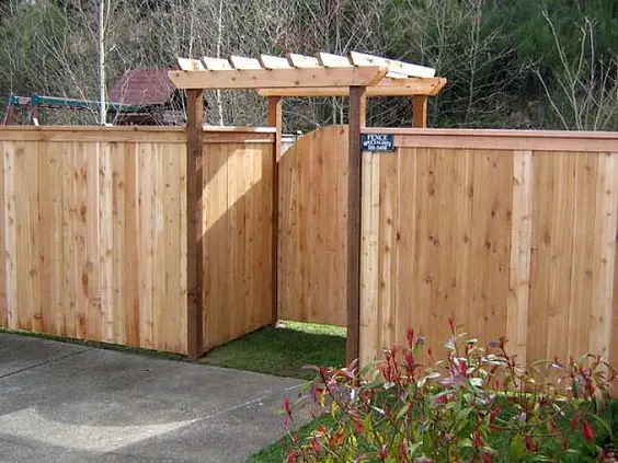 Cedar Fence and Pergola: Bare cedar boards with a pergola frame over the gate