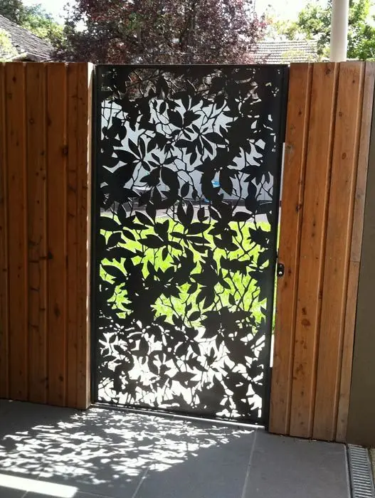 Etched Metal Fence Door: A leaf-and-branch pattern etched into a steel gate softens an otherwise stern fence