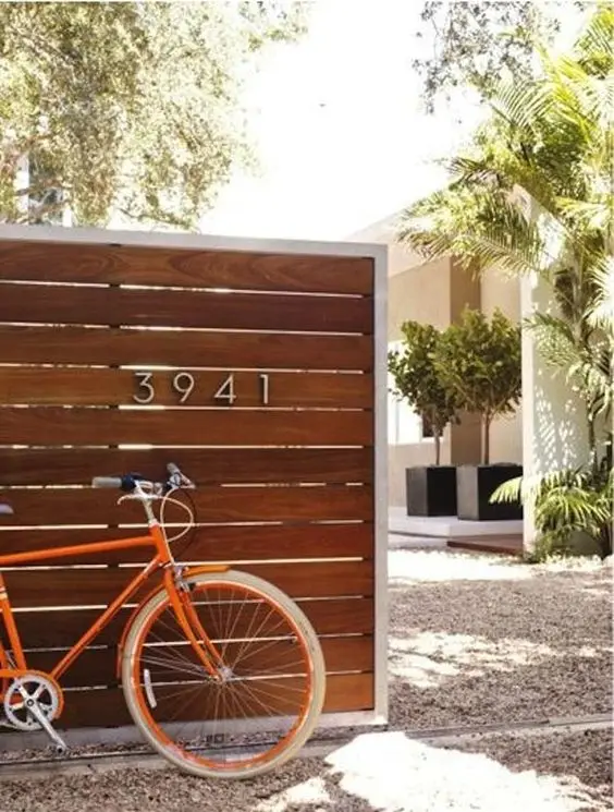 Slatted Wood Fence: Warm cedar boards run horizontally, with a chrome house number to sharpen it up