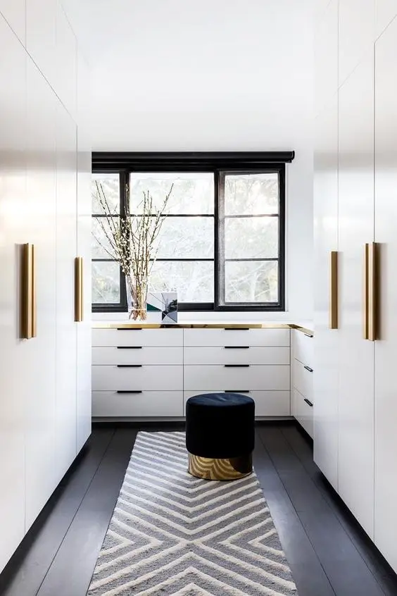 Elegant Minimalist bedroom closet: Wall cabinets, a wide window, white interiors and gold trimmings. Stunningly elegant