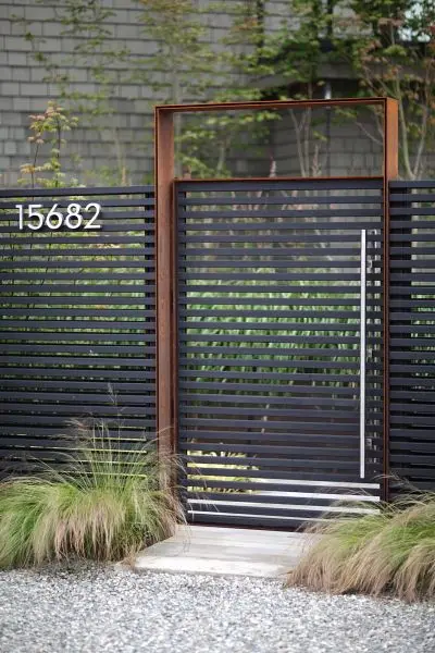 Minimalist Metal Slats front gate: Grey vertical slats, an iron frame, a chrome handle and matching house numbers
