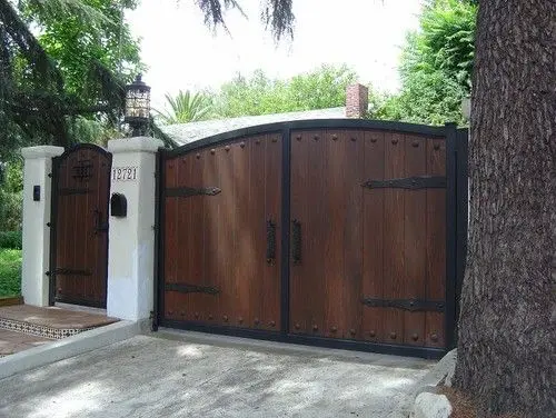 Gothic Wood front gate: Heavy dark boards, black steel strap hinges, and the general suggestion of a moat