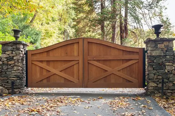 Cedarwood Farmhouse front gate: Cedar boards between stacked-stone posts, across the full driveway width