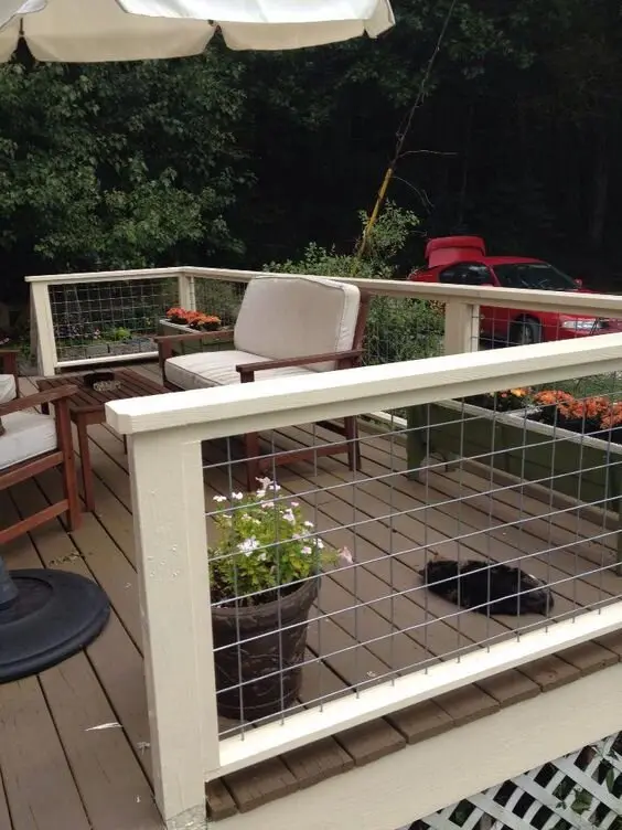 Cosy Farmhouse deck and patio: Timber planks, white railing with hog-wire infill, flower boxes and one oversized umbrella
