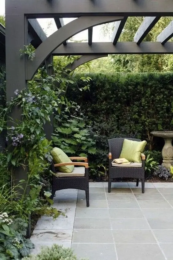 Timeless Elegance deck and patio: Arched pergola supports, concrete tiles underfoot and a living green fence behind rattan