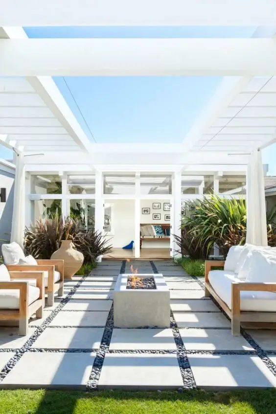 Pavers and Pebbles deck and patio: Garden pavers set in pebbles, a white curtained pergola, and a concrete fire pit down the