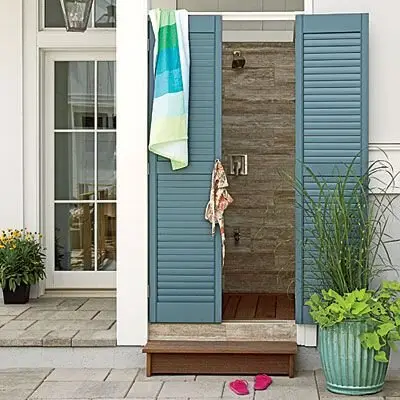 Shutter Doors outdoor shower: Rock tile walls, plank floors and shutter doors in Turkish blue. The shutters deliver full