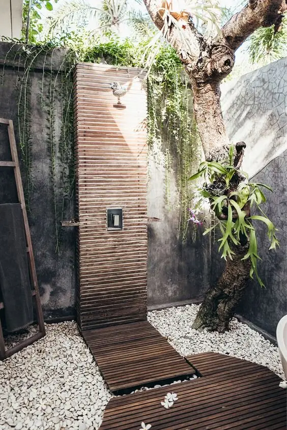Rustic Zen outdoor shower: A timber slat base, white pebbles across the rest of the corner, orchids and climbers, and an