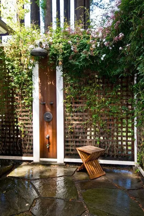 Screens and Climbers outdoor shower: Flagstones, timber screen fencing and flowering climbers filling the gaps. Jasmine or