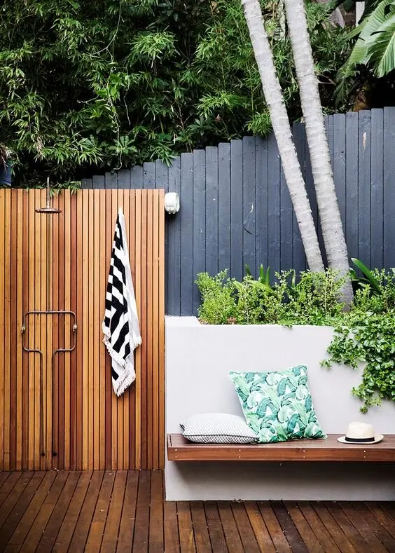 Modern Tropical outdoor shower: A slatted timber wall and floor, with a seat built into a concrete planter full of greenery