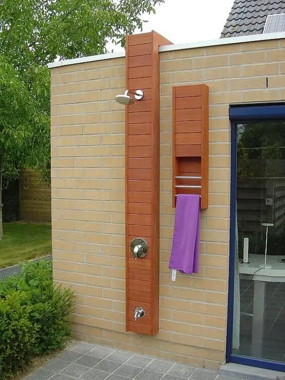 Bricked Modern outdoor shower: A custom timber panel on an existing brick wall carries the pole, the storage and the towel