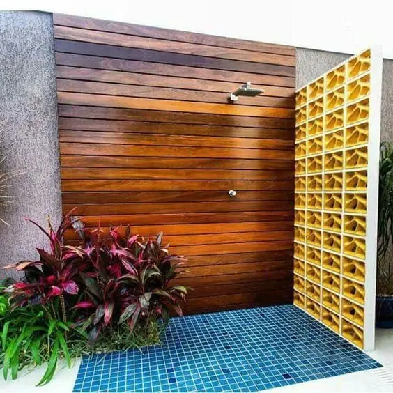 Privacy Screen outdoor shower: Blue tiles underfoot, timber on the wall, a concrete screen one side and plants the other