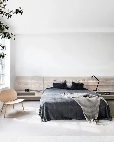 Scandinavian Elegance bedroom: White interior, built-in headboard and side tables, then a chair, a plant and a lamp