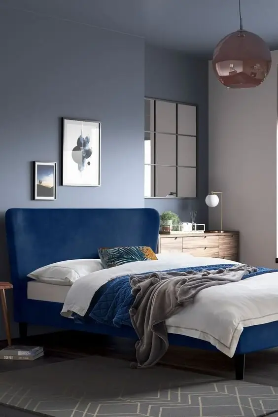 Blue Glam bedroom: A deep navy bed against cool grey walls, with a window-pane mirror and a glass dome pendant