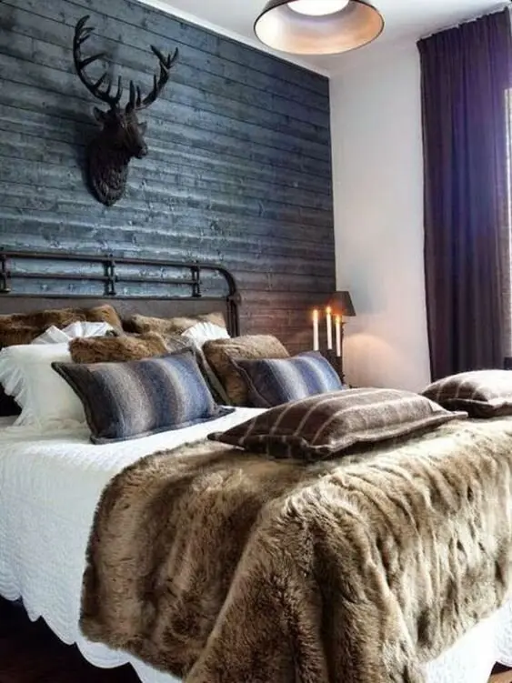 Hunter’s Lodge bedroom: Corrugated iron on the wall, an iron-framed bed, antlers above it