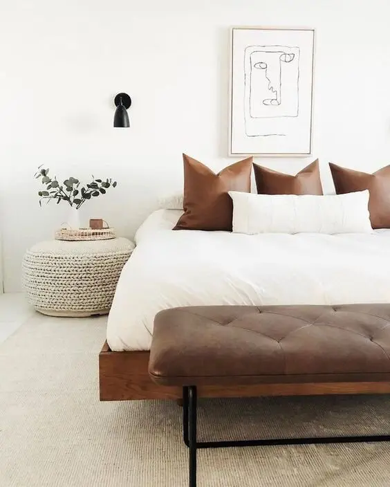 Bright Boho bedroom: Light neutrals, a woven pouf, a seagrass rug and a leather bench at the foot of the bed