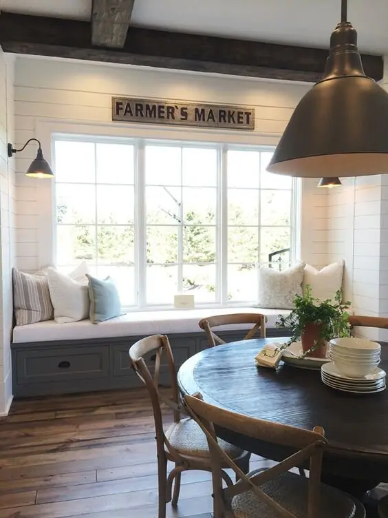 A Window Seat farmhouse kitchen: A wide window with a bench seat built under it, right in the kitchen. Somewhere to sit that