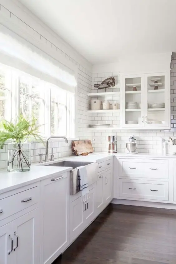 Timeless White farmhouse kitchen: White cabinetry, subway tiles, an apron sink, silver hardware and wide windows. This is