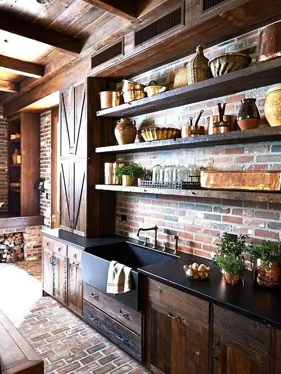 Vintage Opulence farmhouse kitchen: Brick walls and floors, a barn door, handcrafted cabinets and black granite benchtops