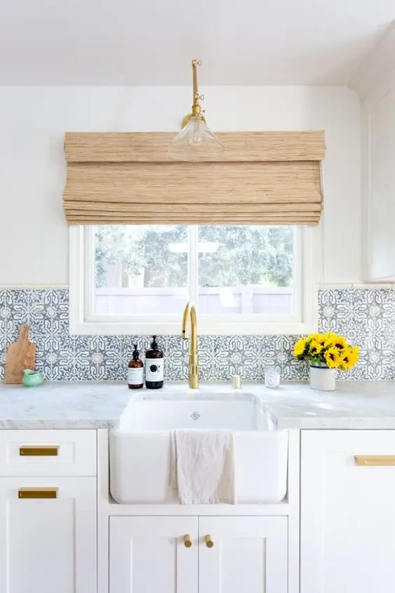 Splendid Splashback farmhouse kitchen: White walls, marble bench, apron sink, and then a light blue Spanish-pattern