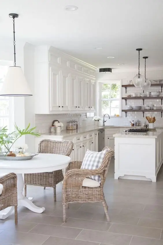 Wicker Charms farmhouse kitchen: White cabinets, glass pendants and wicker dining chairs pushing the whole thing gently