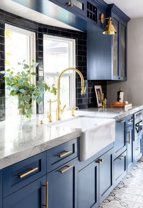 Blue and Beautiful farmhouse kitchen: Deep steel-blue cabinets under pale marble, with brass details. Blue is the easiest