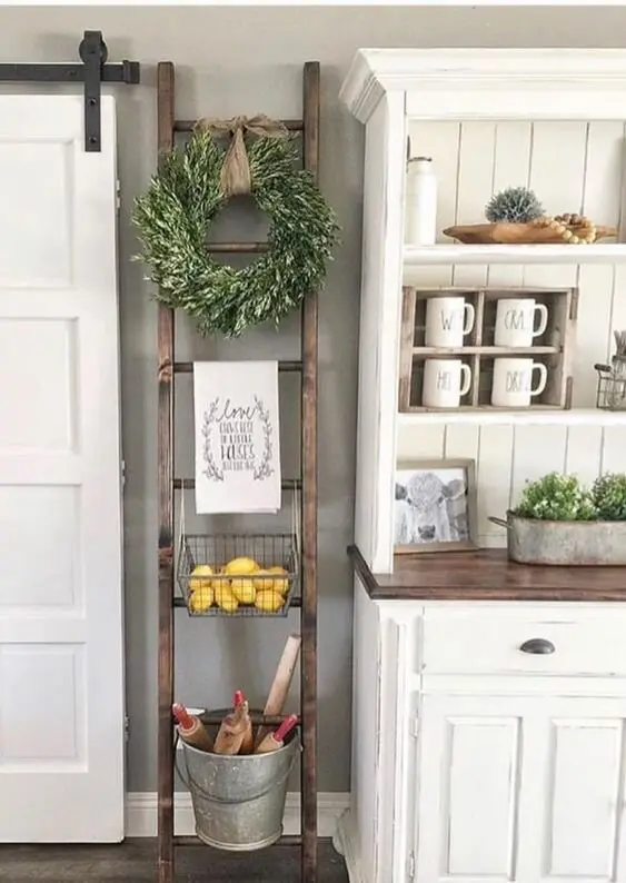 Cottage Ladder farmhouse kitchen: A DIY ladder leaned against shiplap, holding a wire basket, a tin pail and towel bars