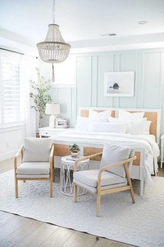 Timeless Coastal coastal bedroom: A seashell chandelier, rattan chairs, a wicker-framed bed and white walls. It could be a