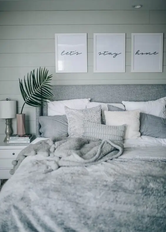Cosy Grey coastal bedroom: Pearl grey shiplap, a stone-textured headboard and greys layered through the linen. Overcast-day