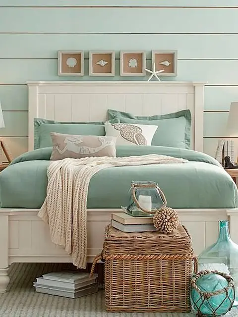 Coastal Greens coastal bedroom: Mint green shiplap, green bedding and glass decor, with starfish and shell accents. Green