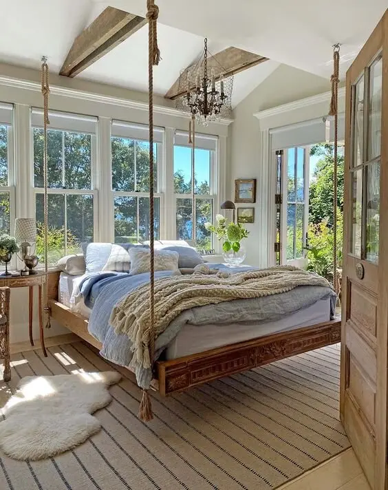 Hanging Bed coastal bedroom: A bed hung from exposed beams, swaying gently in front of window walls. It's the hammock idea