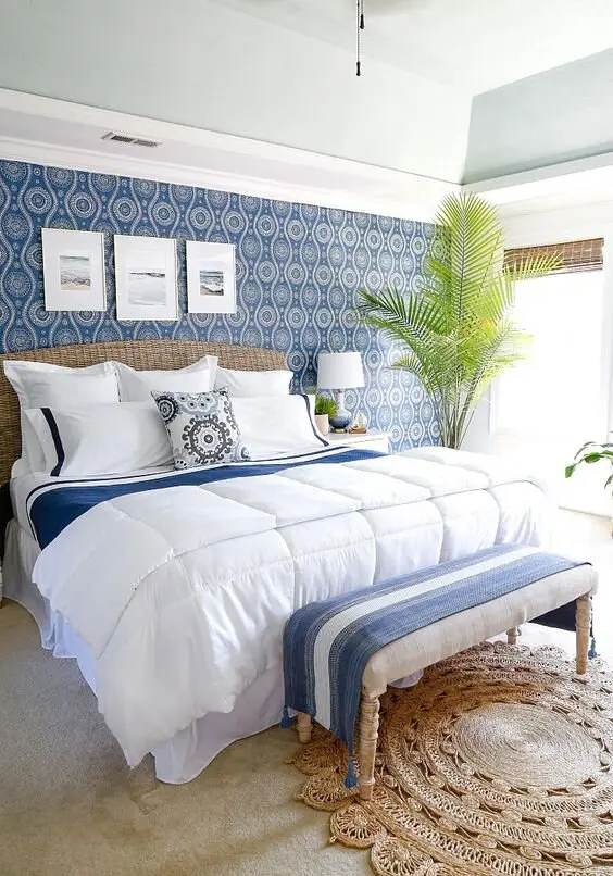 Blue Tropics coastal bedroom: A light blue ceiling over white walls and sand-toned floors, with bright blue accents for