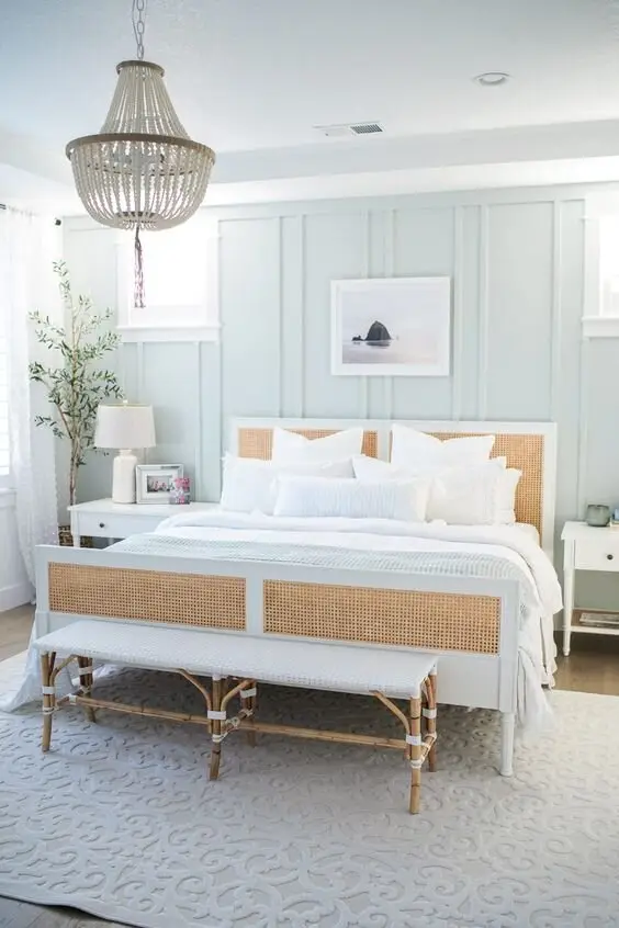 Seaside Cottage coastal bedroom: Rattan head and foot boards, a wicker bench, a shell chandelier and a textured white rug