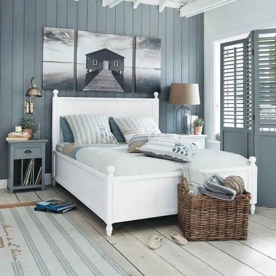 Blue Beach House coastal bedroom: Steel blue walls, vertical shiplap, a white box bed and plank floors, with an accordion