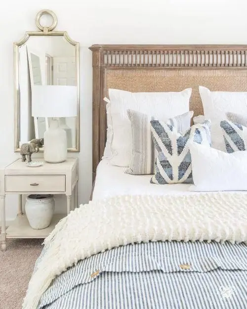 Ancestral Pieces coastal bedroom: A vintage headboard, a shabby chic night table, an old mirror, with blue and white pulling