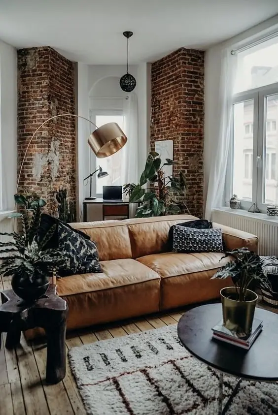 The Leather Couch industrial living room: The classic leather couch brings in strong industrial vibes to this snug and charming apartment