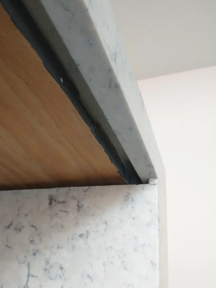 Close-up of a stone benchtop edge meeting a timber panel